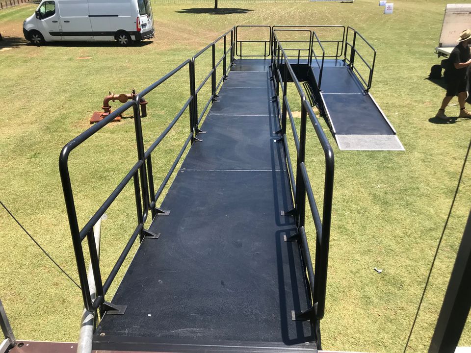 Handrailed access ramp leading up to a platform on grass