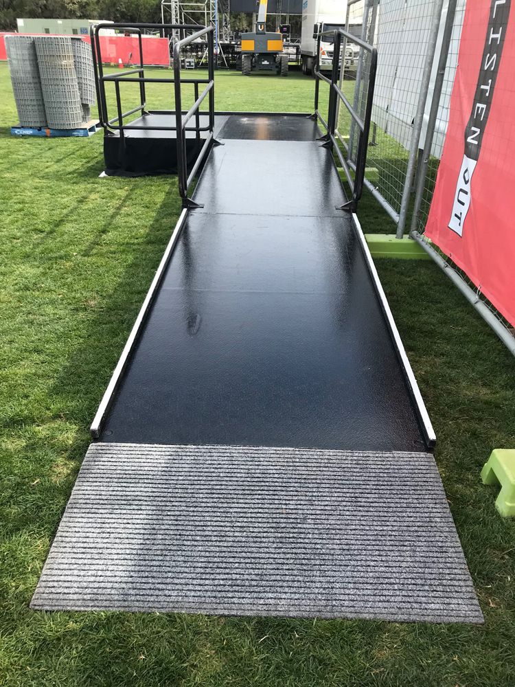 Black walkway ramp with matting laid across grass