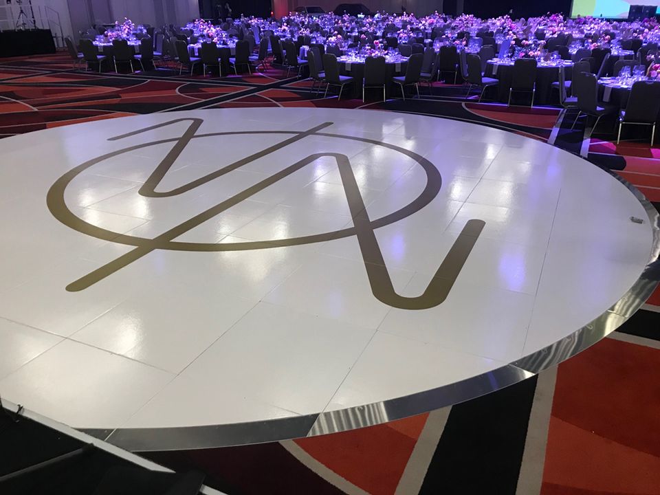 Round white floor with a large gold monogram at a gala dinner