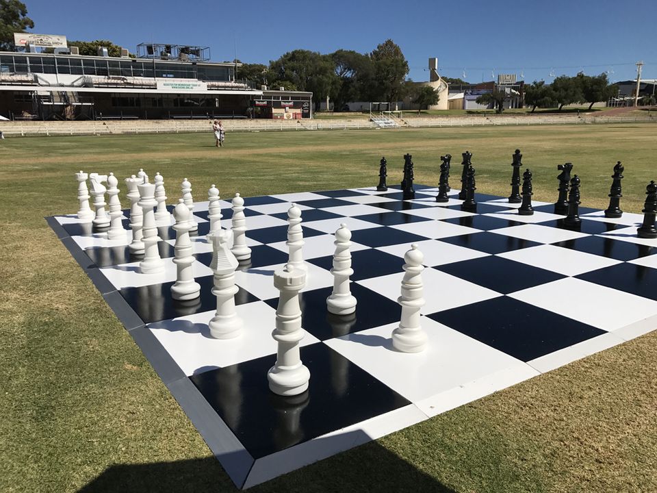 Black and white checkered floor on grass set up as a giant chess board