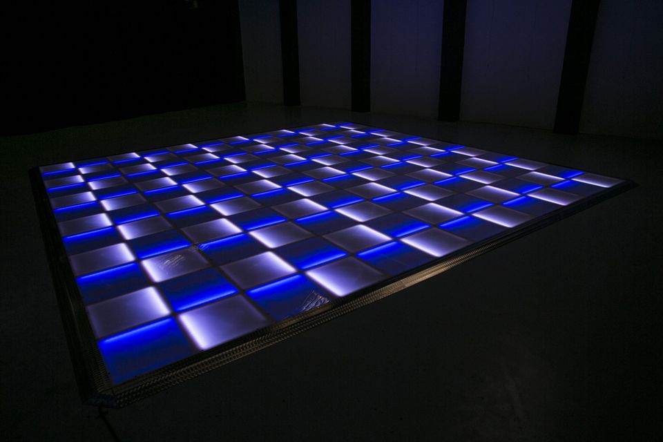 LED dance floor panels lit blue and white in a dark room