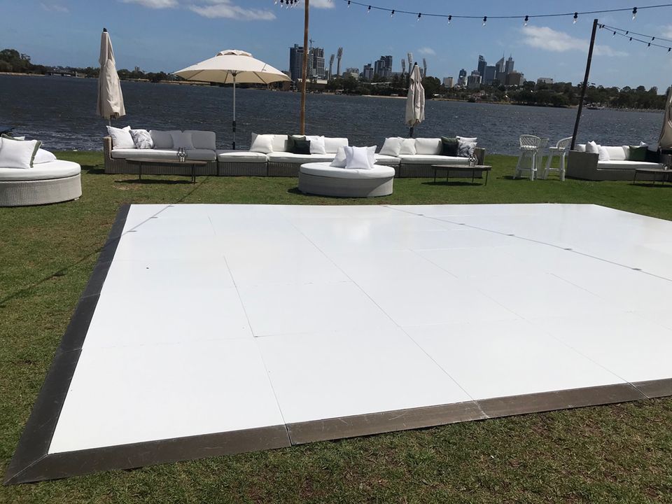 White gloss dance floor on a riverside lawn with lounge furniture