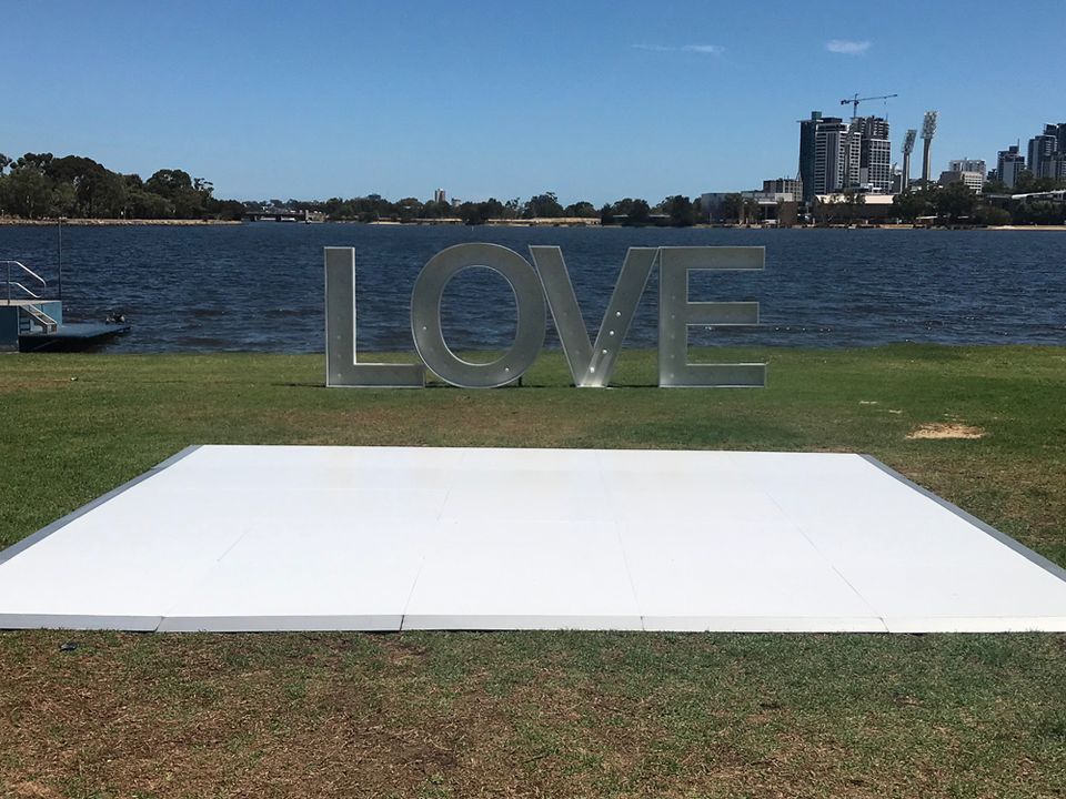 White gloss dance floor on grass beside the river with large LOVE letters