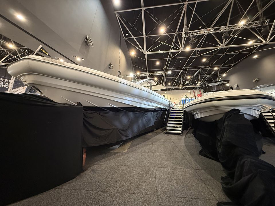 Row of boats on raised display stages with black skirting in an exhibition hall