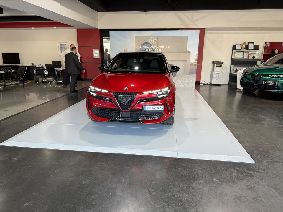 Red SUV on a raised white gloss display platform in a car showroom