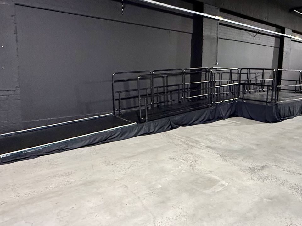 Black access ramp with handrails rising to a railed viewing platform