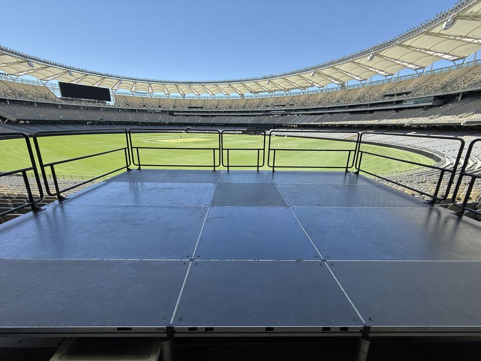 Railed black platform built over stadium seating, overlooking the field