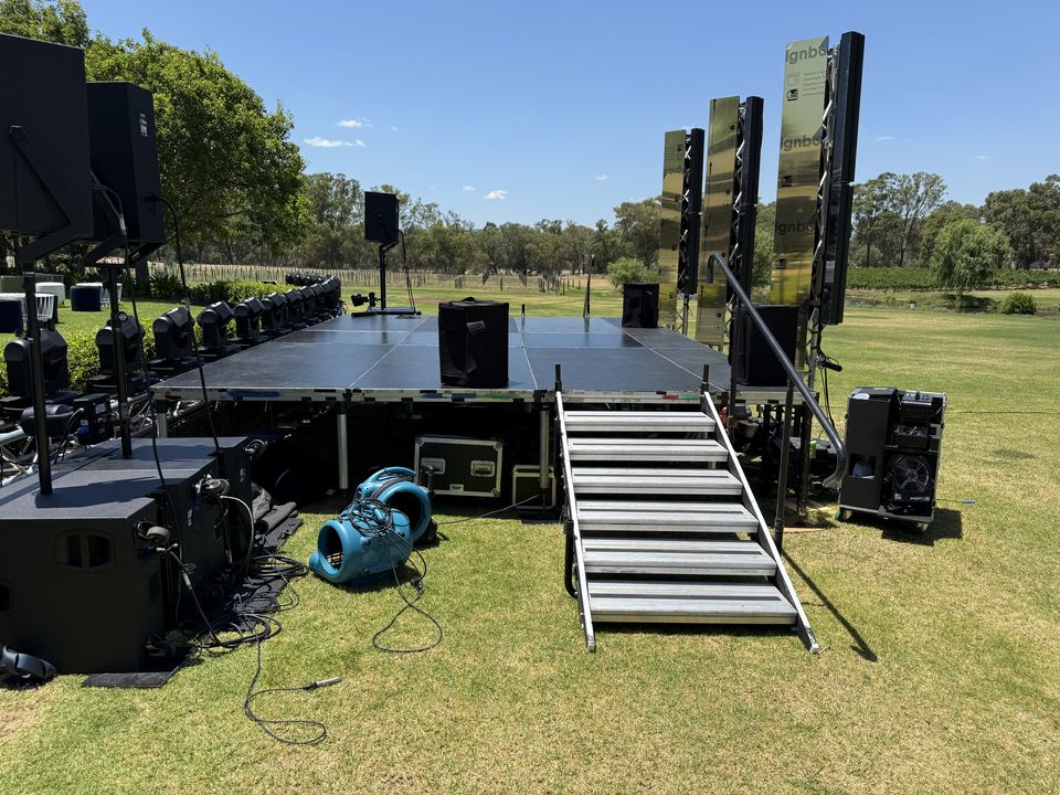 Outdoor stage on grass in a park with aluminium stairs and a handrail