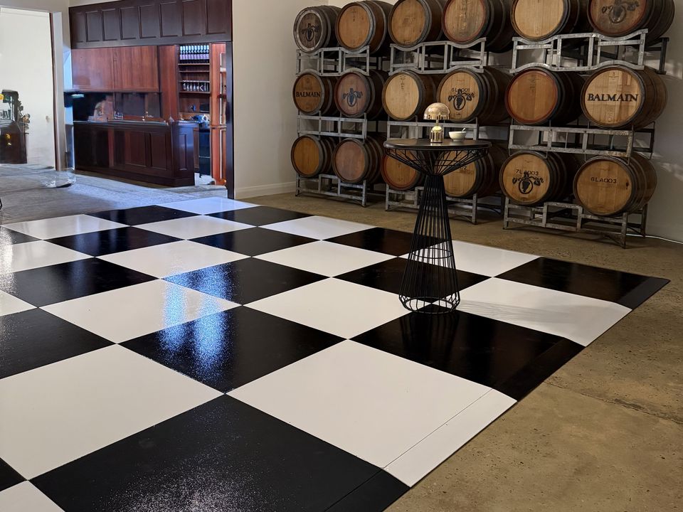 Black and white checkered dance floor in a room lined with wine barrels