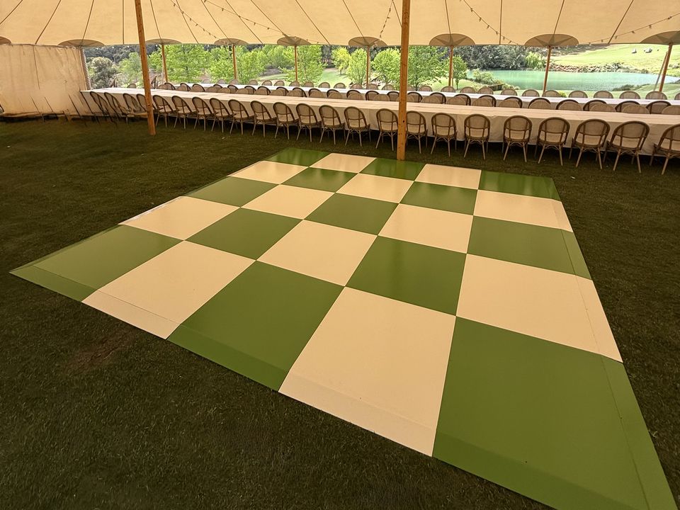 Green and white checkered dance floor on grass under a sailcloth tent