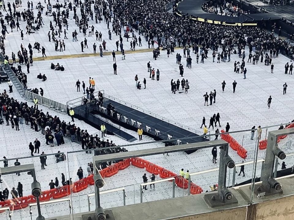 Aerial view of a raised, railed platform with ramps on a stadium concert floor