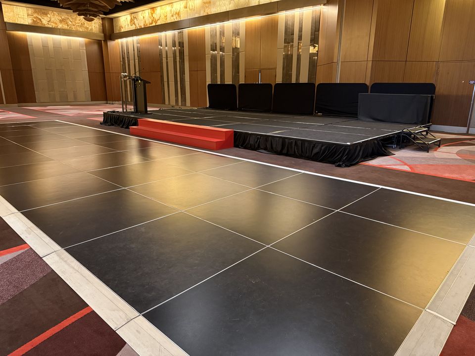 Black dance floor with white edging in front of a skirted stage with steps