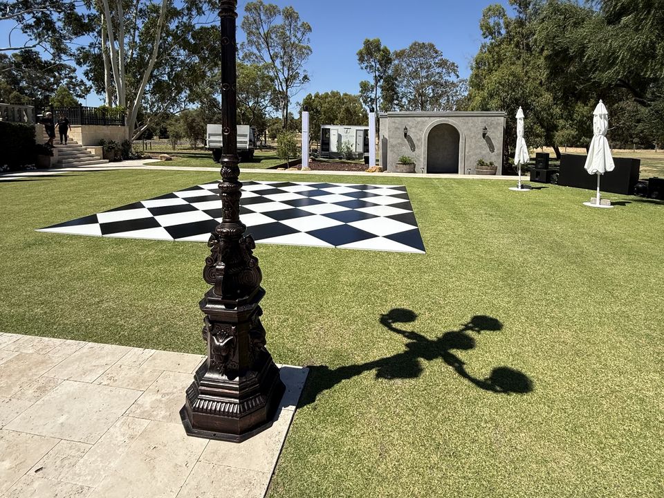 Black and white checkered dance floor on a lawn beside an ornate lamp post